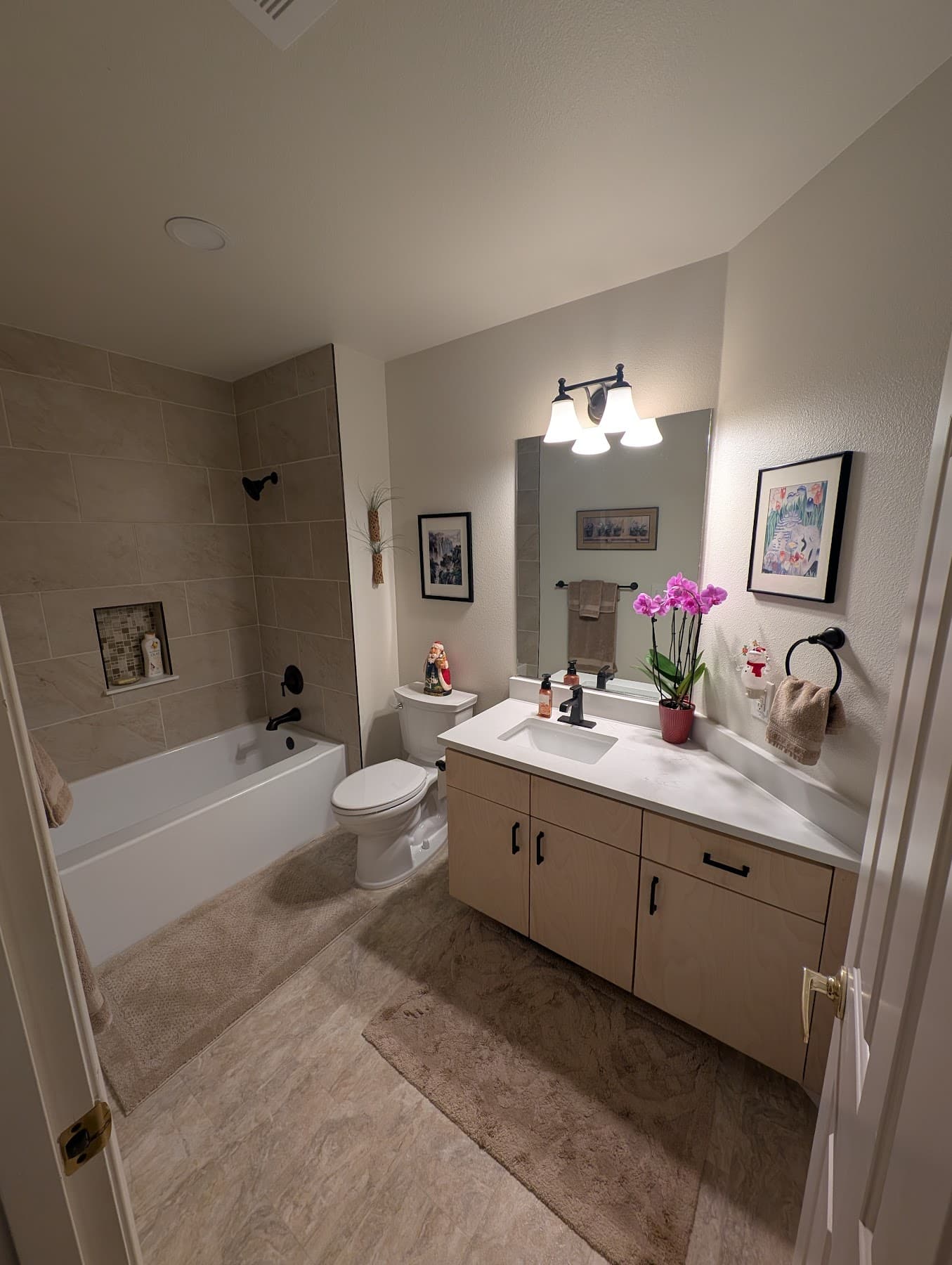 Hall bathroom with tiled tub surround and new vanity after remodel